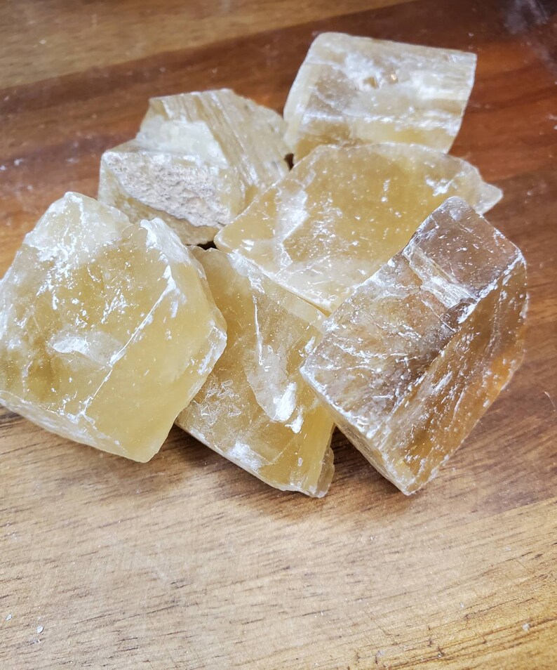 May include: A group of seven translucent, honey-colored calcite crystals. The crystals are rough and have a natural, unpolished finish.