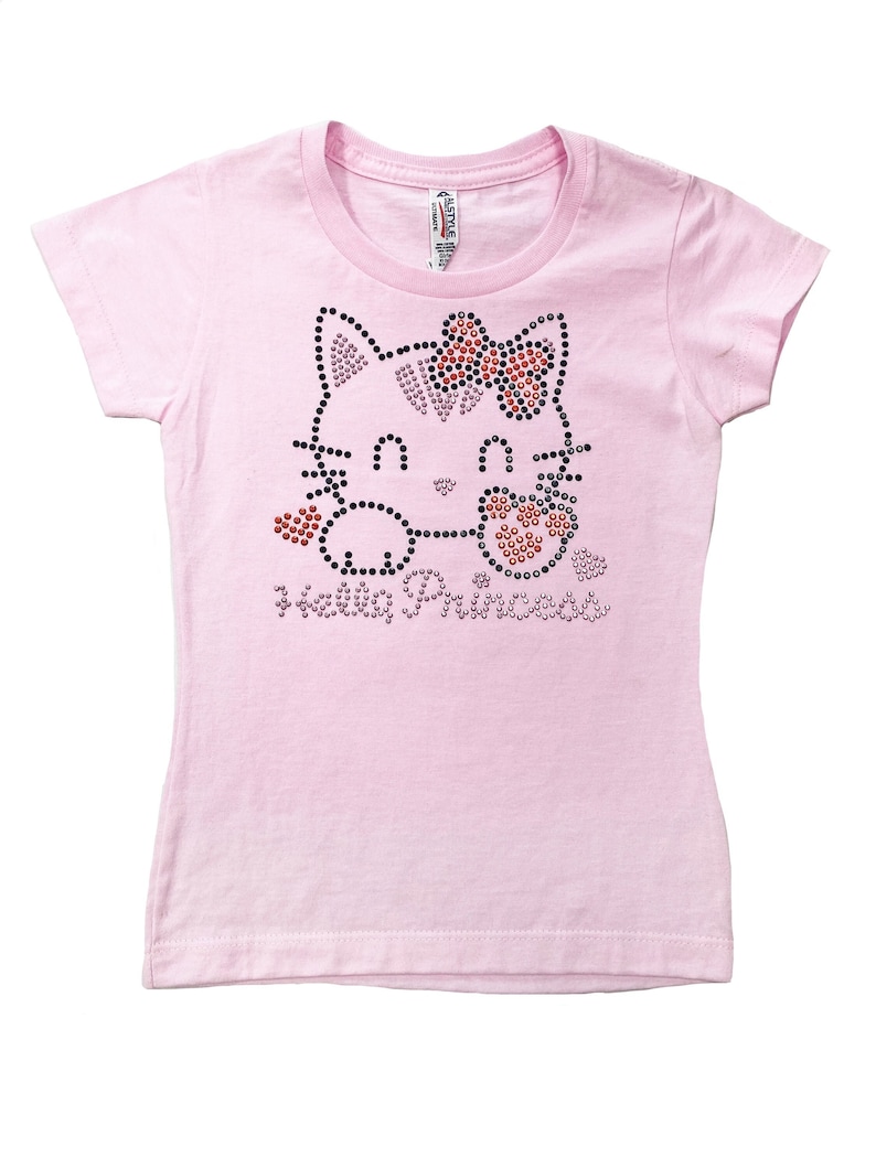 May include: Pink t-shirt with a rhinestone Hello Kitty design. The design features a Hello Kitty face with a bow, hearts, and the words "Hello Princess".