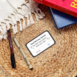 May include: A white phone screen with a message that reads "Good Morning, Gemini! The Stars have spoken about your day!" with two buttons, "Cancel" and "OK".