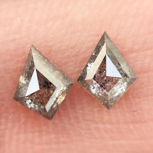 Op de afbeelding: Twee kleine, heldere, gefacetteerde, vlieger-vormige diamanten in grijs, bruin en zwart.