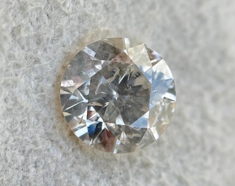 May include: A clear round diamond gemstone with many facets.