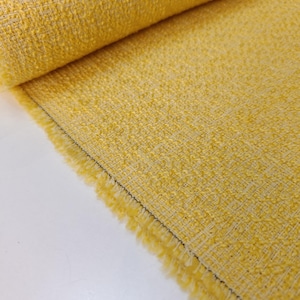 Puede incluir: Primer plano de un rollo de tela amarillo brillante con un tejido texturizado. La tela tiene un borde deshilachado con una línea de costura negra. El material está tejido apretado y parece ser un textil de peso medio, adecuado para varios proyectos de costura.