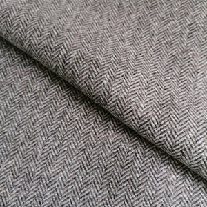May include: Close-up of a brown and white herringbone fabric. The fabric has a subtle texture and a woven pattern.
