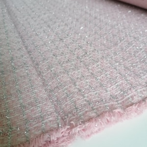 May include: Pink fabric with a silver glitter woven into the fabric. The fabric has a fringe edge.