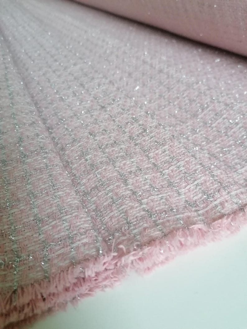 May include: Pink fabric with a silver glitter woven into the fabric. The fabric has a fringe edge.