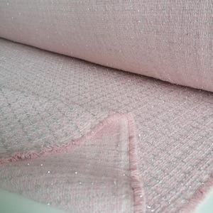 May include: Pink fabric with silver glitter woven into the fabric. The fabric has a textured, slightly fuzzy surface.