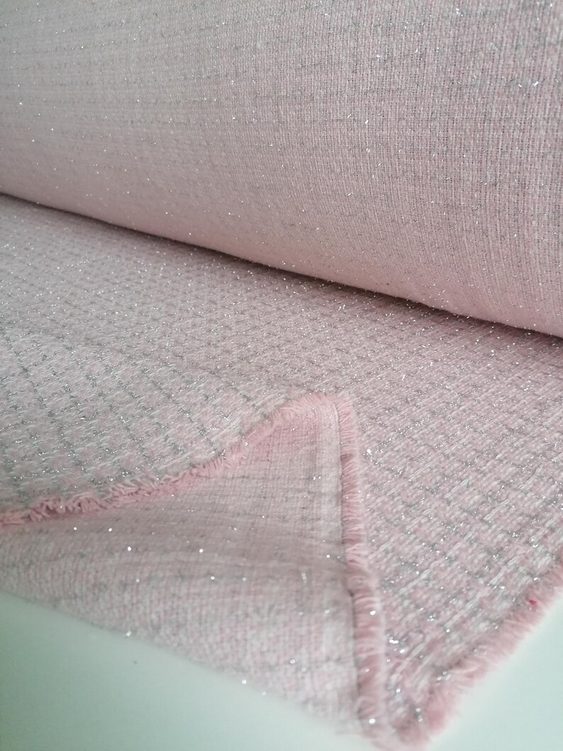May include: Pink fabric with silver glitter woven into the fabric. The fabric has a textured, slightly fuzzy surface.