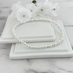 May include: A silver beaded bracelet with a simple design. The bracelet is made of small, round beads that are strung together on a thin silver chain.