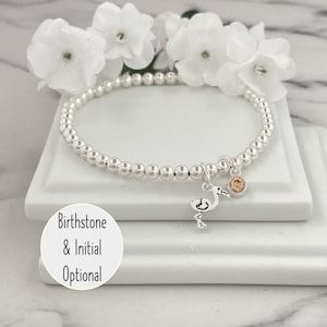 May include: Silver beaded bracelet with a small bird charm and a birthstone charm. Birthstone & Initial Optional.