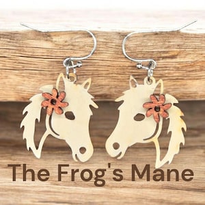 May include: A pair of earrings featuring a horse head design with a wooden flower accent. The earrings are made of light-colored wood and have silver-colored ear wires. The text "The Frog's Mane" is at the bottom.