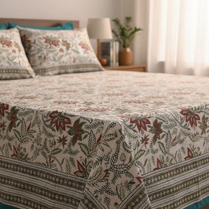 May include: Cream-colored floral bedspread and pillow set with a repeating pattern of red and green flowers and leaves. The bedspread has a dark green border and teal trim. The pillows are visible on the bed.