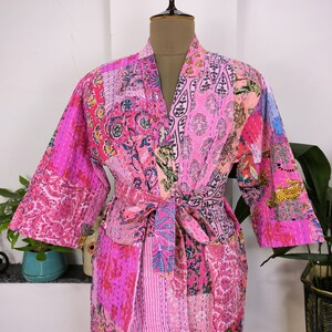 May include: A pink and white patchwork kimono robe with a floral print and a tie belt.