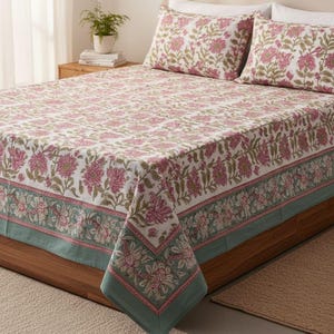 Peut inclure: Un ensemble de literie à motifs floraux, avec un fond blanc et des motifs floraux roses et verts. L'ensemble comprend un couvre-lit et deux taies d'oreiller. Le couvre-lit a une bordure verte avec des motifs floraux. Le lit est en bois.