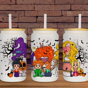 May include: Three white glass tumblers with bamboo lids and straws, each featuring a Halloween-themed design. The designs include cartoon witches, pumpkins, bats, and spiderwebs. The tumblers are set against a brick background.
