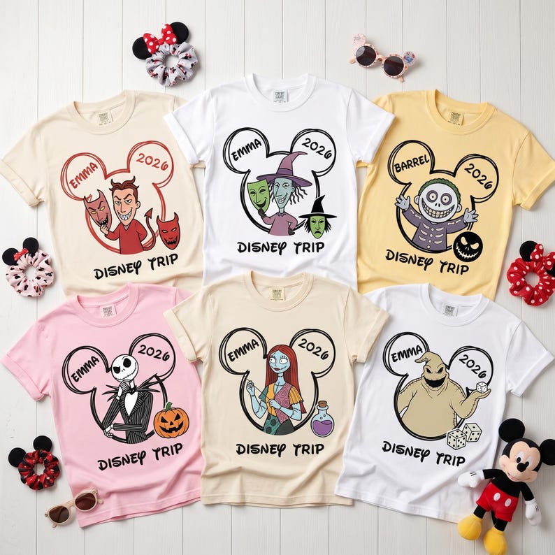 May include: Six short-sleeve t-shirts in various pastel colors featuring Nightmare Before Christmas characters inside Mickey Mouse ear outlines. Each shirt displays the name EMMA, the year 2026, and the text DISNEY TRIP. Includes hair scrunchies.
