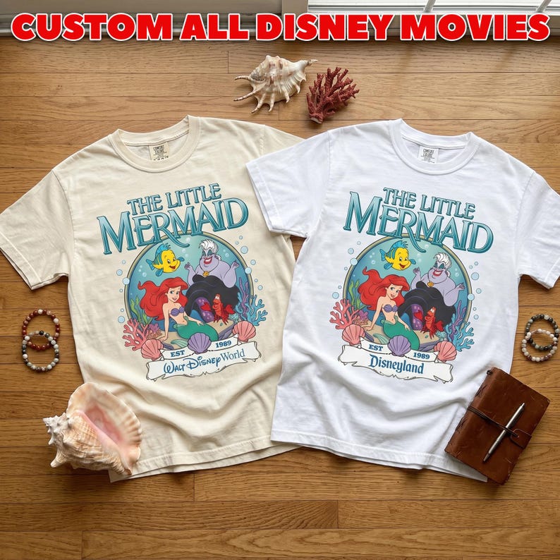 May include: Two t-shirts featuring "The Little Mermaid" graphic. One is cream-colored, the other white. The design includes Ariel, Flounder, and Ursula. The text "CUSTOM ALL DISNEY MOVIES" is at the top. One shirt says "Walt Disney World" and the other says "Disneyland".