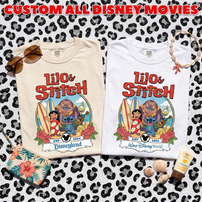Op de afbeelding: Twee T-shirts, &eacute;&eacute;n cr&egrave;me en &eacute;&eacute;n wit, met een kleurrijke afbeelding van Lilo & Stitch met surfplanken en bloemen. Het cr&egrave;mekleurige shirt zegt "Disneyland" en het witte shirt zegt "Walt Disney World." De tekst "CUSTOM ALL DISNEY MOVIES" staat bovenaan.