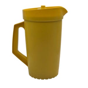 Op de afbeelding: Een felgele plastic kan met een cilindrisch lichaam, een stevig handvat aan de zijkant en een bijpassend deksel met een kleine centrale knop. De onderkant van de kan heeft een verticale ribbelstructuur en de bovenkant bevat een schenktuit.