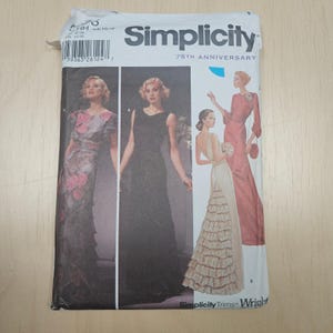 May include: A Simplicity sewing pattern packet featuring illustrations of elegant evening gowns. The packet has a white background with the text "Simplicity" and "75th Anniversary". The gowns are in shades of black, pink, and cream.