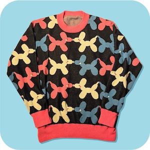 Könnte beinhalten: Schwarzer Pullover mit einem sich wiederholenden Muster aus Ballonhunden in Rosa, Gelb und Blau. Der Pullover hat einen rosa Ausschnitt und Bündchen. Ein lustiges und farbenfrohes Strickstück.