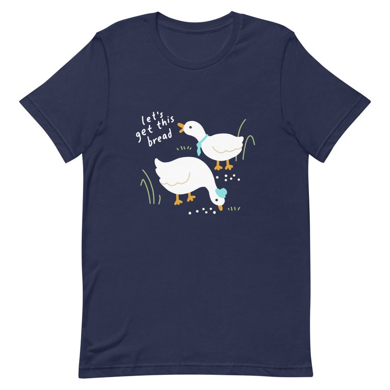 May include: A navy blue t-shirt featuring a white goose design and the text "Let's get this bread".