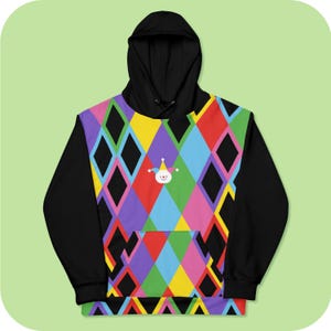 Pode incluir: Hoodie preto com um padrão de diamantes coloridos e um pequeno rosto de palhaço de desenho animado na frente.