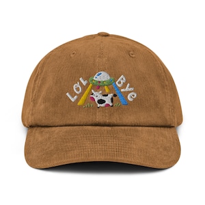 May include: A brown corduroy baseball cap featuring an embroidered design of a cow being abducted by a UFO. The design also includes the text "LOL Bye".