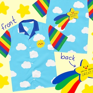 Peut inclure: Chemise bleu clair à motif nuages et soleil. Les manches ont des rayures arc-en-ciel. Le dos de la chemise présente une étoile filante avec le texte "you're doing GREAT!" Un design amusant et fantaisiste.