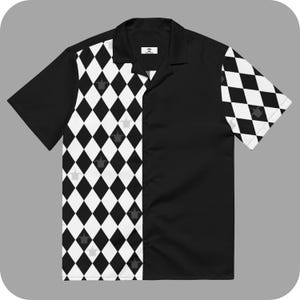 May include: A black and white short-sleeved button-up shirt with a diamond pattern on the left side and a solid black right side. The shirt has a collar and a button-up front.