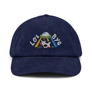 May include: A navy blue corduroy baseball cap with an embroidered design of a cow being abducted by a UFO. The text "LOL Bye" is embroidered above the design.