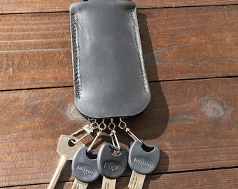 May include: Black leather key holder with a flap closure and four silver keys with black plastic heads. The keys are labeled "Mul-T-Lock".