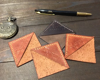 May include: Four leather bookmarks with stitched edges. The bookmarks are in the shape of a triangle with rounded corners. The bookmarks are brown and orange with gold lettering. The lettering on the bookmarks reads "Keep Exploring", "Keep Creating", "Keep Dreaming", and "Keep Trying".