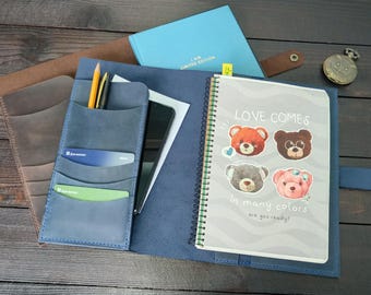 May include: A blue leather organizer folio containing a spiral-bound notebook with four bear illustrations and the text "LOVE COMES in many colors are you ready?". The folio features card slots, a pen holder, and a separate light blue notebook.