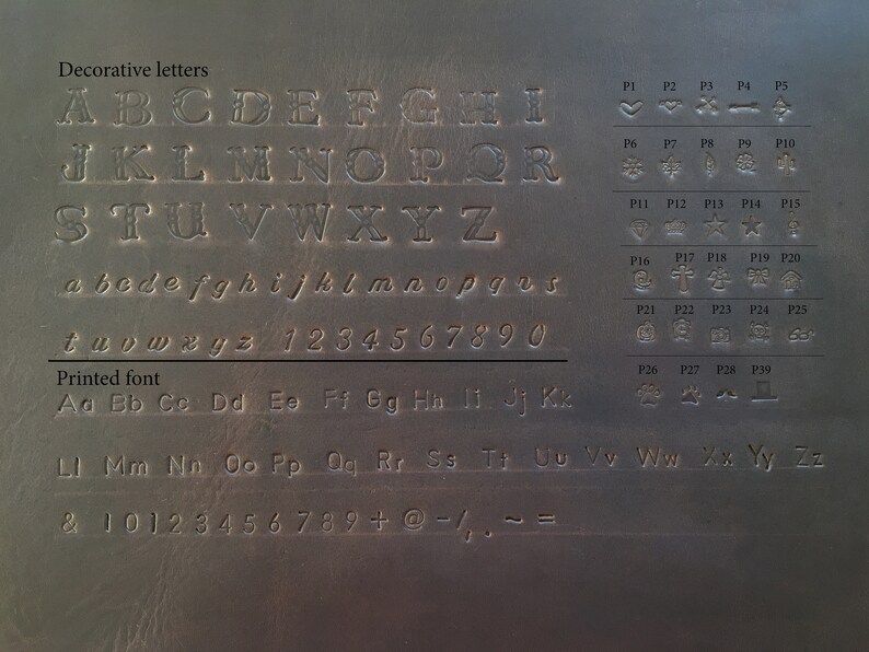 May include: A close-up of a brown leather surface with a variety of decorative letters, numbers, and symbols. The letters are in a decorative font and the numbers are in a printed font. The symbols are in a variety of styles.