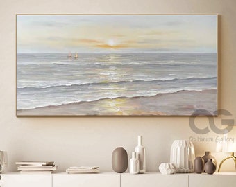 May include: A painting of a seascape with a sunset in the background. The painting is in a light brown frame and is hanging on a white wall above a white cabinet. There are decorative items on the cabinet, including vases and a lamp.