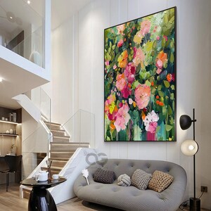 May include: A large abstract painting of a floral bouquet with pink, red, orange, and yellow flowers on a green background. The painting is hanging on a white wall in a modern living room.