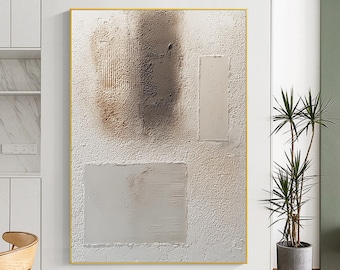 Op de afbeelding: Abstracte, getextureerde wandkunst in een gouden lijst. Het kunstwerk heeft een witte achtergrond met gelaagde rechthoekige en organische vormen in tinten bruin en beige. Het getextureerde oppervlak voegt diepte en visuele interesse toe aan het stuk.