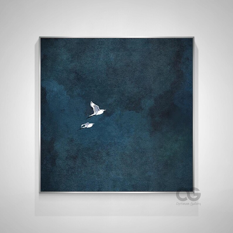 May include: Framed wall art showing two white birds soaring against a dark blue and teal backdrop. The artwork has a watercolour effect, with soft edges and a textured appearance. The birds are detailed with black and grey markings.