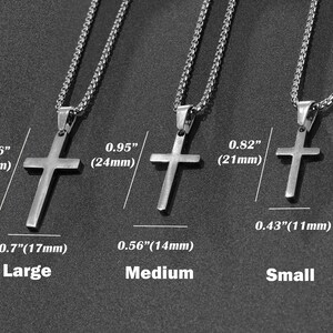 May include: Three silver cross necklaces in different sizes: large, medium, and small. The necklaces are shown against a dark gray background. The cross pendants are 1.26 inches (32 mm), 0.95 inches (24 mm), and 0.82 inches (21 mm) in size.