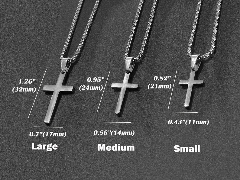 May include: Three silver cross necklaces in different sizes: large, medium, and small. The necklaces are shown against a dark gray background. The cross pendants are 1.26 inches (32 mm), 0.95 inches (24 mm), and 0.82 inches (21 mm) in size.