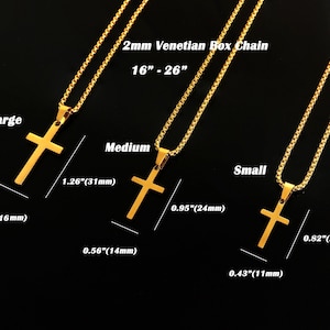 May include: Three gold cross pendants on chains, with measurements in inches and millimeters. The largest cross is 1.26 inches (31 millimeters) tall and 0.7 inches (16 millimeters) wide. The medium cross is 0.95 inches (24 millimeters) tall and 0.56 inches (14 millimeters) wide. The smallest cross is 0.82 inches (20 millimeters) tall and 0.43 inches (11 millimeters) wide. The chains are 2mm Venetian box chains.