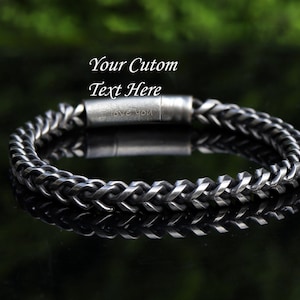 May include: A silver braided chain bracelet with a magnetic clasp. The bracelet has a personalized inscription that reads "Love you".