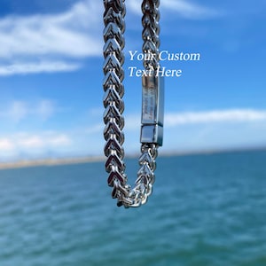 May include: A silver-toned metal chain bracelet featuring a rectangular clasp with the engraved text "I love you more every second" and the overlaid white text "Your Custom Text Here" positioned above the clasp on the metallic surface.