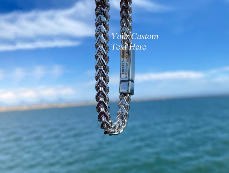 May include: A silver-toned metal chain bracelet featuring a rectangular clasp with the engraved text "I love you more every second" and the overlaid white text "Your Custom Text Here" positioned above the clasp on the metallic surface.