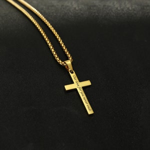 May include: Gold chain necklace with a gold cross pendant. The cross has the inscription "Our love for you never ends".