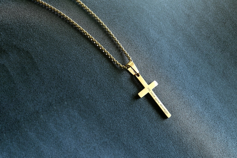 May include: A gold chain necklace with a gold cross pendant. The cross has the words "I'll love you always" engraved on it.