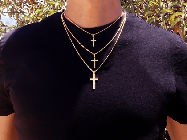 May include: A layered gold chain necklace with three cross pendants of varying sizes.