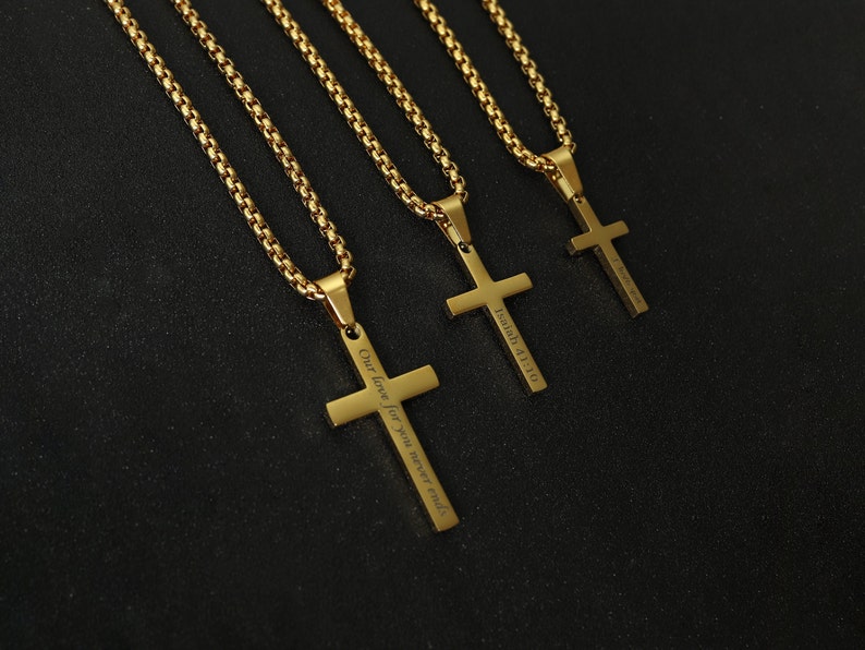 May include: Three gold chains with cross pendants. The cross pendants have different inscriptions: "Our love for you never ends", "Isaiah 41:10", and a third inscription that is not visible in the image.