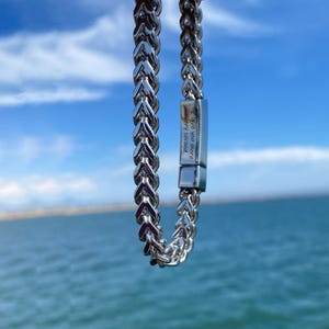 Puede incluir: Un brazalete de cadena de plata con un cierre de plata que dice "Live your most every second".