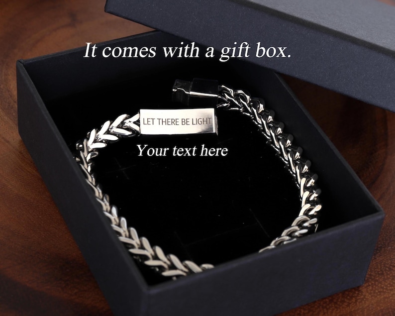 May include: A silver-toned wheat chain bracelet with a rectangular metal clasp featuring the engraved text "LET THERE BE LIGHT" and "Your text here," presented inside a black gift box with the printed text "It comes with a gift box."